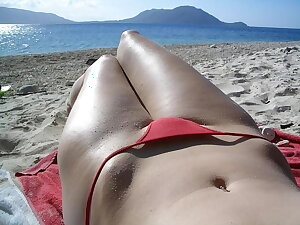 A girl takes a photo of her bikini while sunbathing on the beach.