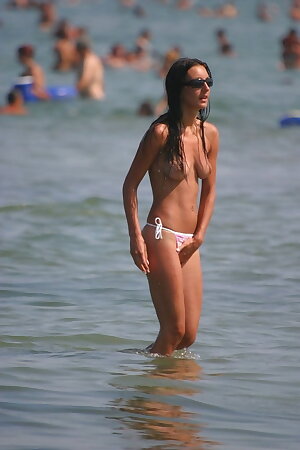 A thin Romanian girl swims topless in the Black Sea.